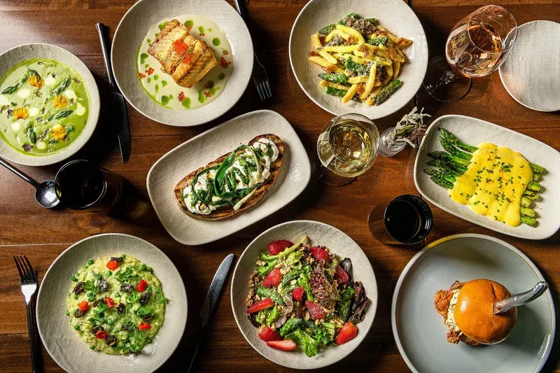 Overhead view of diverse plated food and drinks on a dark wooden table.