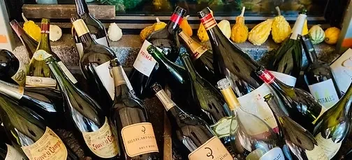 Numerous wine and champagne bottles stacked with decorative gourds.