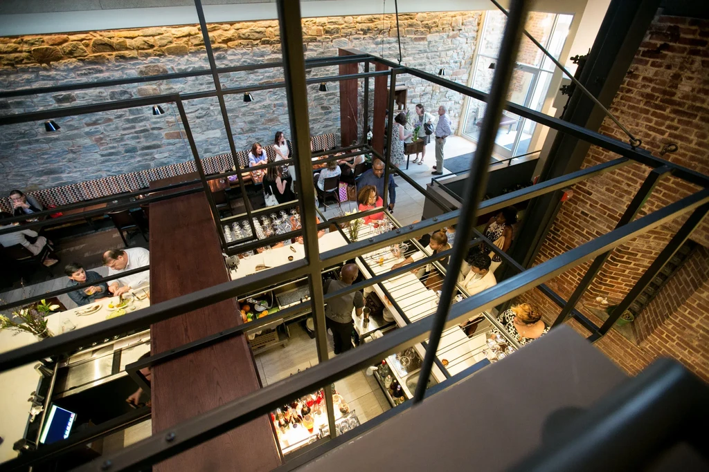 Busy multi-level restaurant and bar interior, stone, wood, and metal.