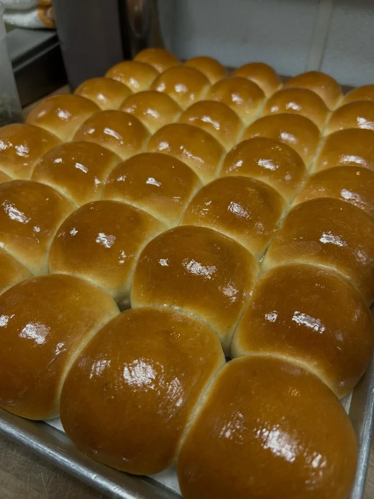 Freshly baked, glossy golden-brown dinner rolls in a baking tray.