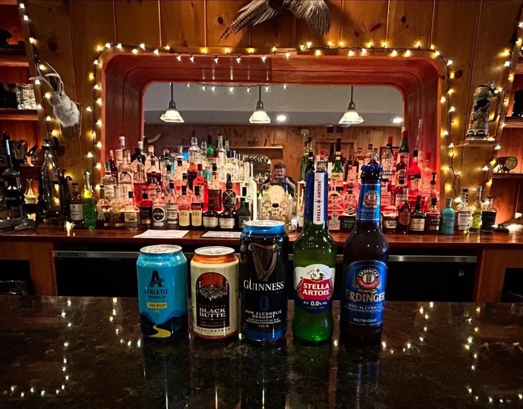 Five non-alcoholic beverages lined on a rustic, well-stocked bar counter.