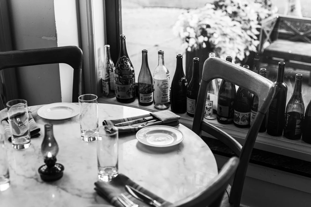 Black and white marble table set by window with empty bottles.