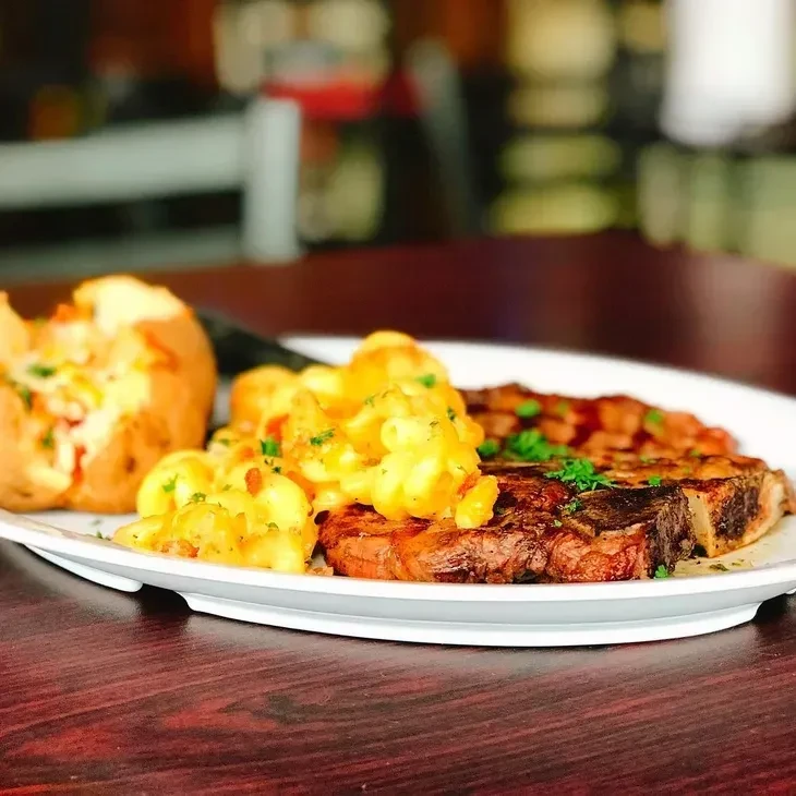 Plate of steak, mac and cheese, loaded baked potato.