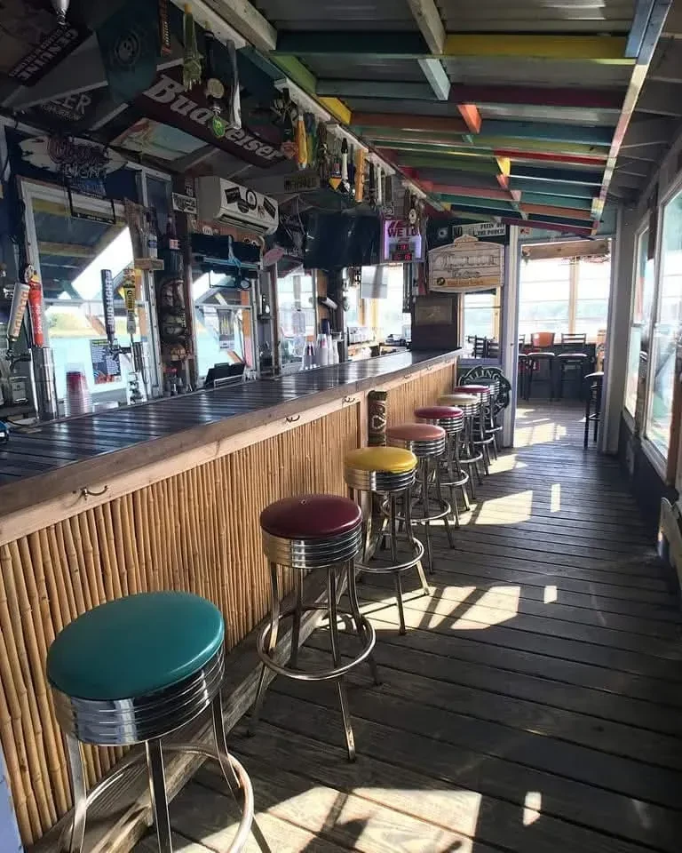 Empty, vibrant bar with a bamboo counter and colorful stools.