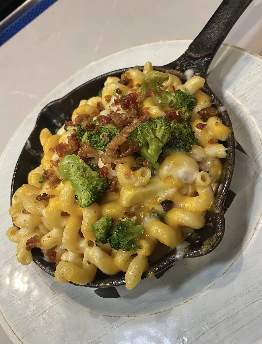 Cast iron skillet of macaroni and cheese with bacon and broccoli
