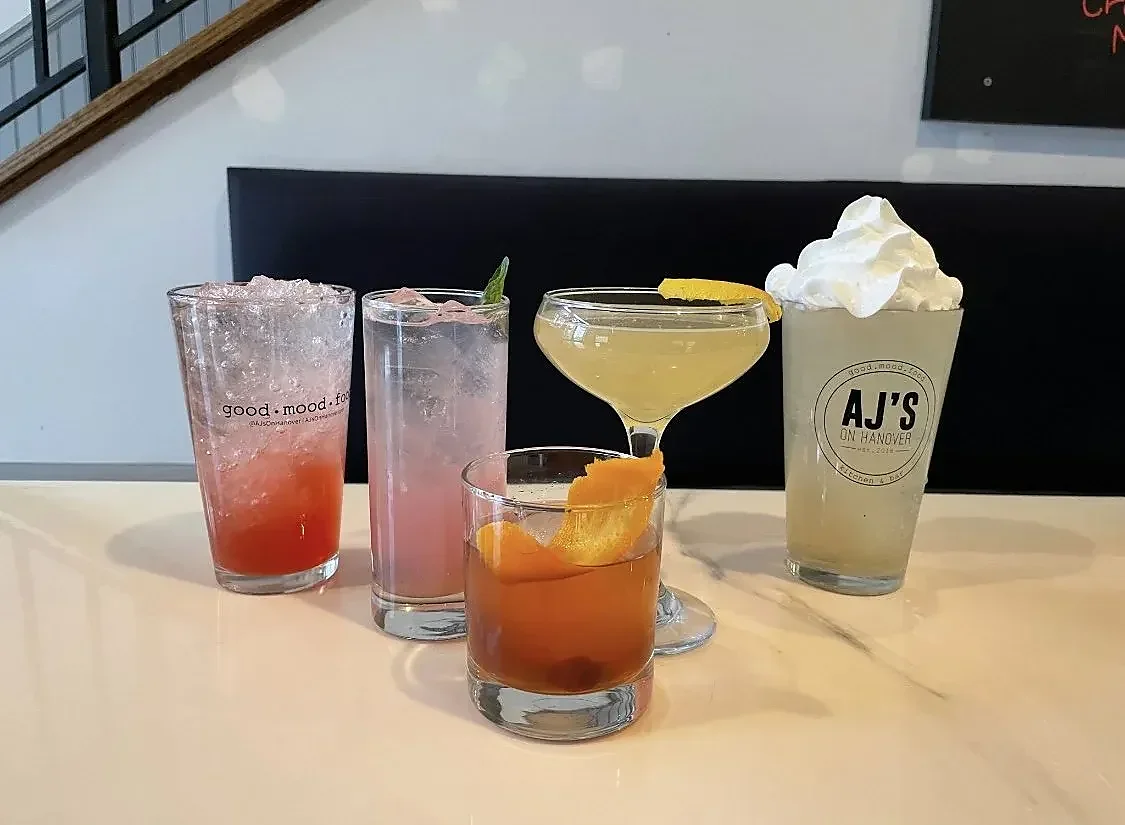 Five mixed cocktails in varied glassware on a bar counter
