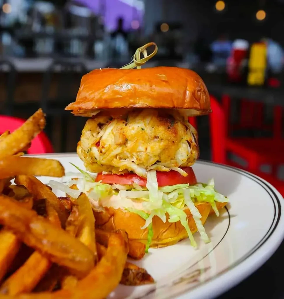 Flaky crab cake sandwich with tomato, lettuce, and fries.