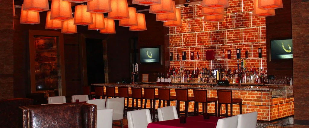 Modern rustic bar interior with warm lighting and Horseshoe TV logos.