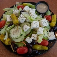 Greek salad with feta, olives, cucumber, tomatoes, peppers, and dressing.