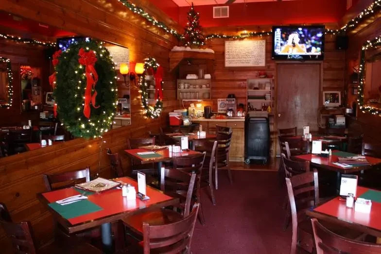 Empty casual restaurant interior, festively decorated for Christmas with red tables.
