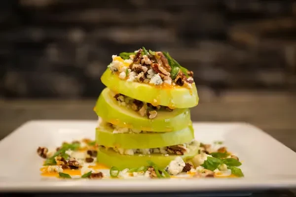 Layered green apple, blue cheese, nuts, herbs, and sauce drizzle.