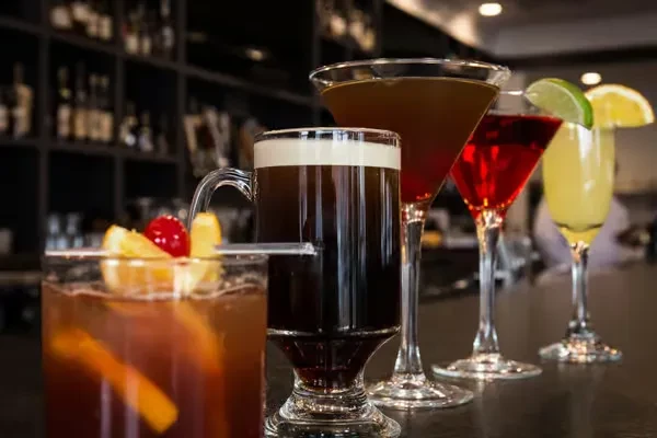 Five different garnished cocktails lined up on a dark bar counter.