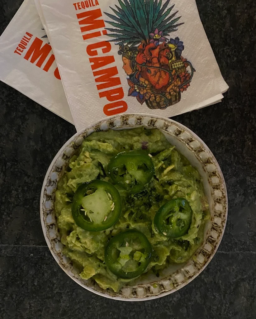 Top-down: Guacamole with jalapeños, 'Mi Campo Tequila' branded napkins.