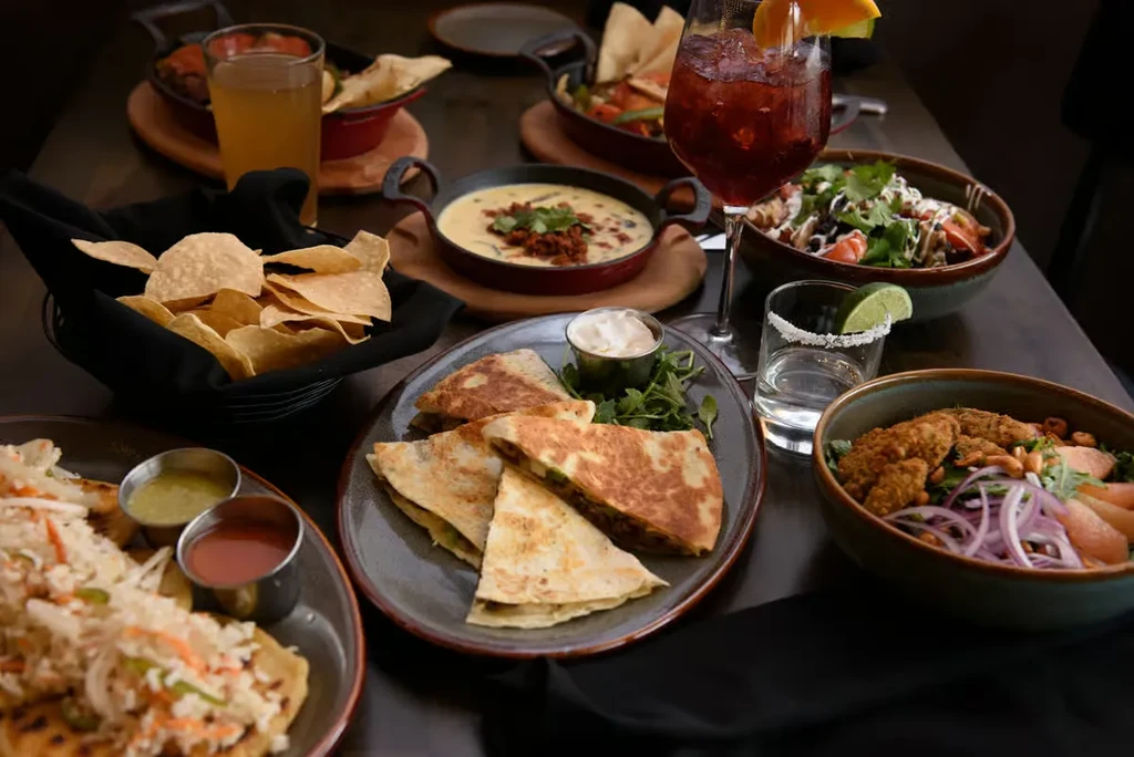 Restaurant table with assorted Mexican food, chips, queso, and drinks.