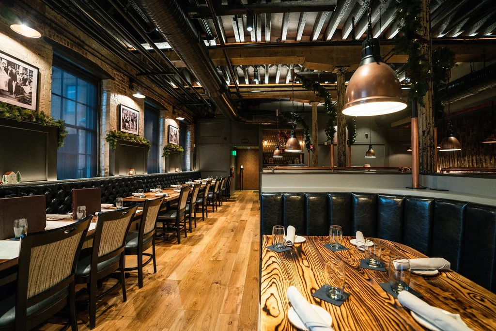 Empty restaurant interior featuring industrial-rustic design and warm lighting.