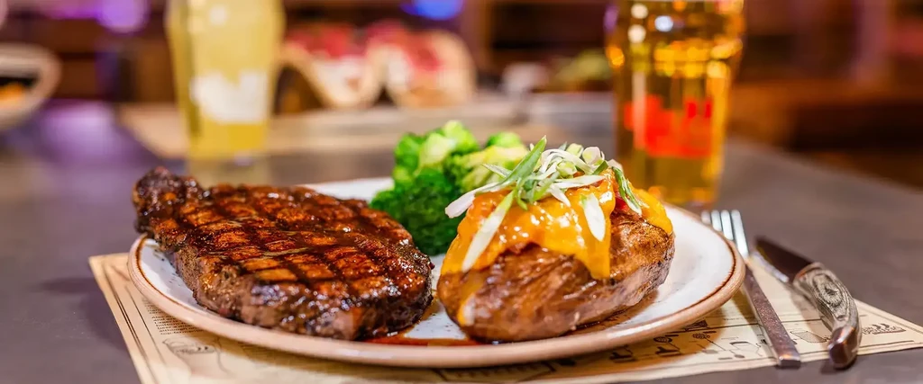 Restaurant meal of grilled steak, loaded potato, and broccoli.