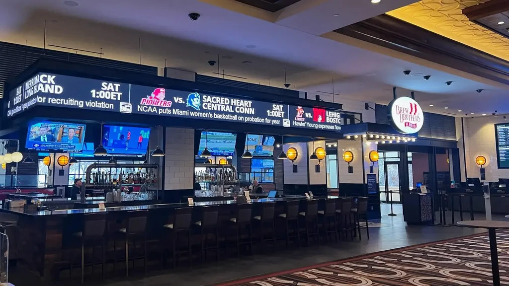 Modern Brew Brothers sports bar with large bar, sports ticker, and TVs.