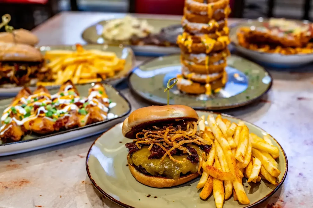 Vibrant spread of burger, fries, onion rings, and loaded potatoes.