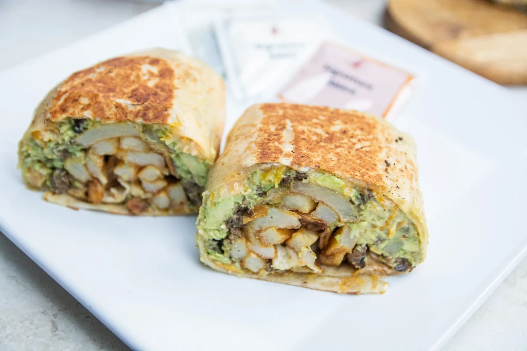Two diagonally cut burrito halves showing meat, potatoes, and guacamole.