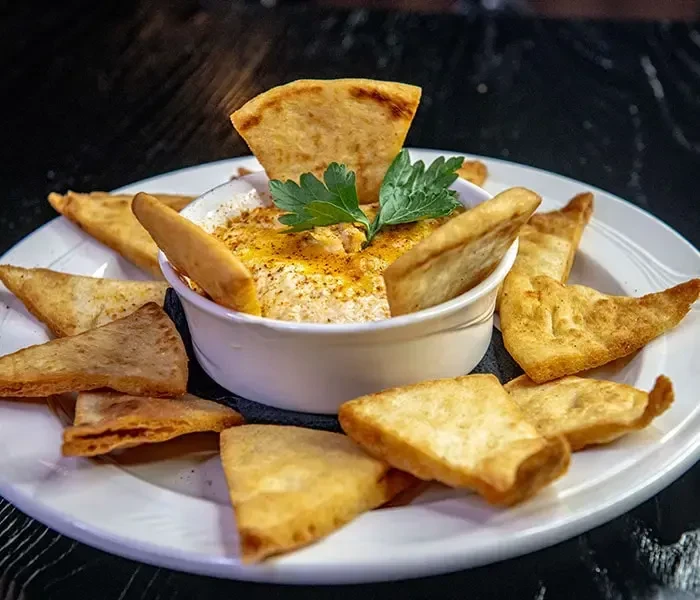 Creamy dip garnished with parsley, paprika, and golden pita chips.