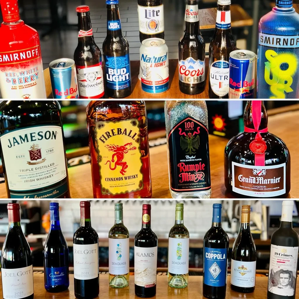 Three sections of beer, spirits, and wine bottles on a bar.
