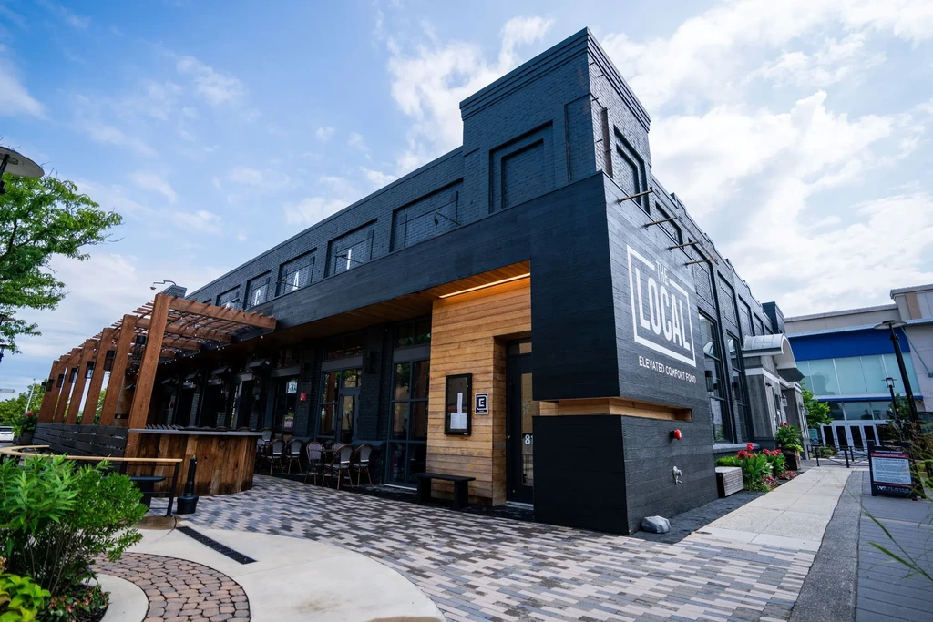 Modern restaurant 'THE LOCAL' with outdoor patio, pergola, and greenery.