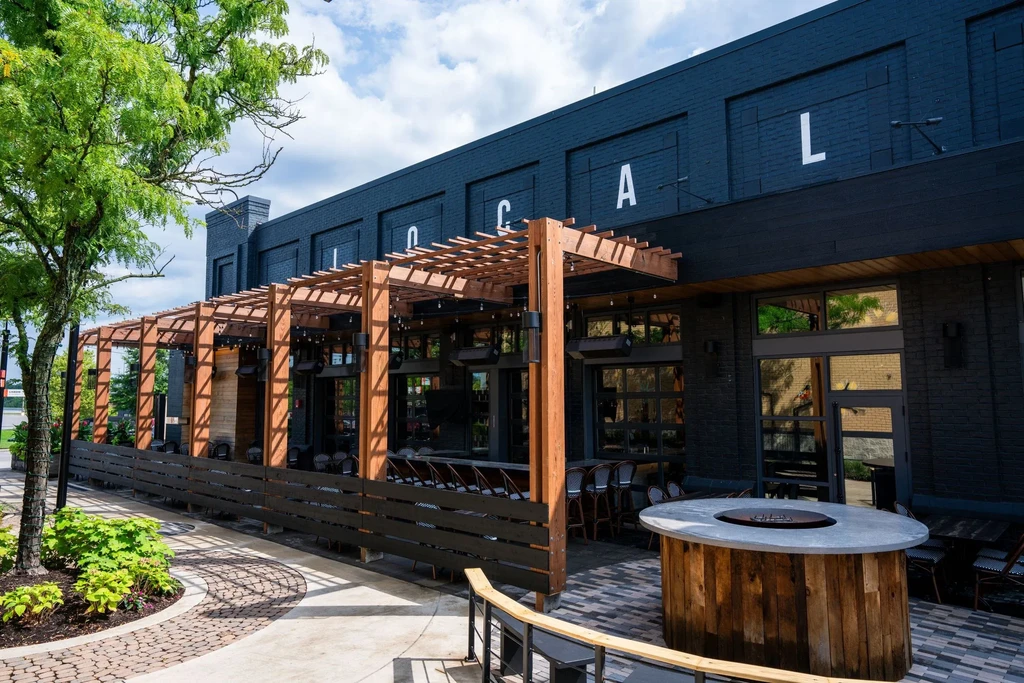 Modern restaurant 'LOCAL' with dark brick and expansive patio under pergola.