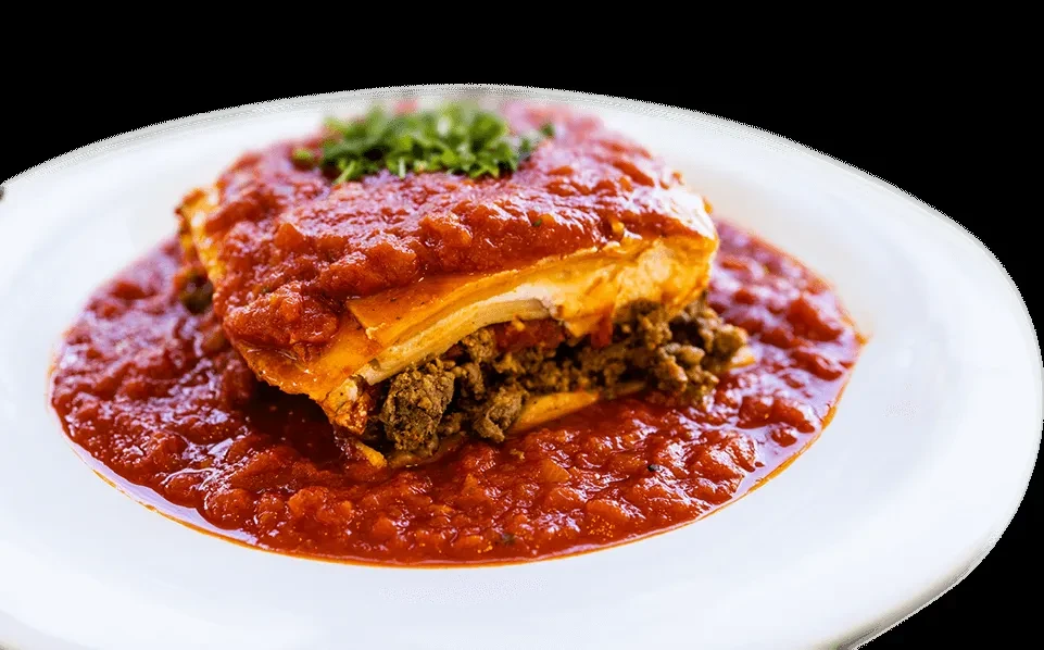 Layered savory casserole, covered in red sauce and garnished with green herbs.