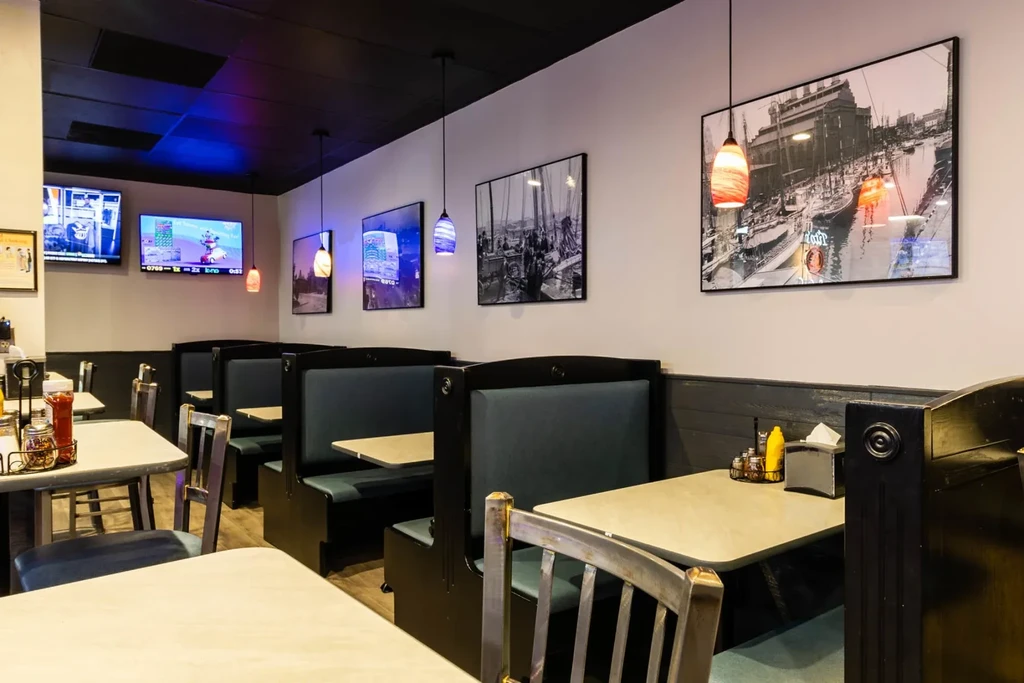 Casual empty restaurant interior with booths, TVs, and colorful pendant lights.