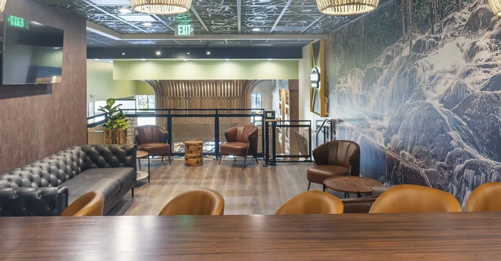 Modern lounge with leather seating, wooden tables, and a large nature mural.
