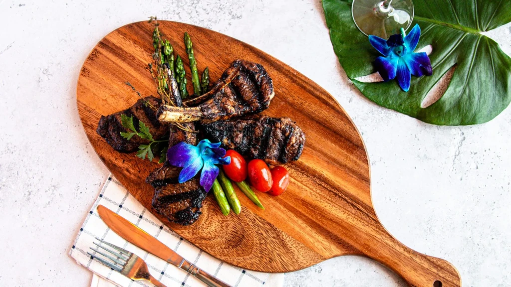 Top-down: Grilled lamb chops with asparagus, tomatoes, and orchids.