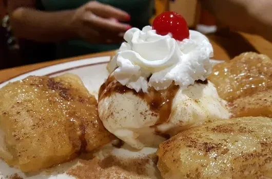Vanilla ice cream with cherry, dark syrup, and glazed fried pastries.
