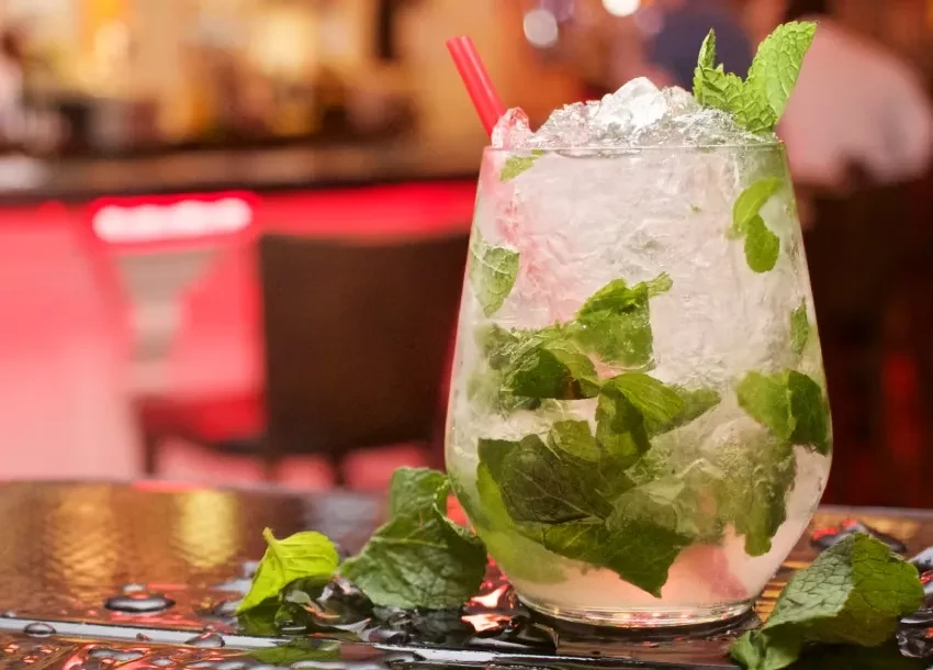Cocktail with crushed ice, green mint, and a red straw.