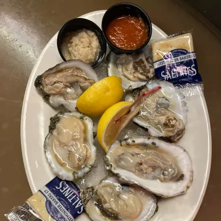 Fresh oysters on ice with lemons, sauces, and saltine crackers.