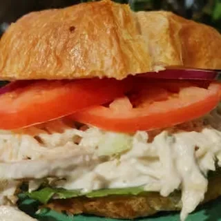 Croissant sandwich filled with chicken salad, tomato, red onion, and lettuce.