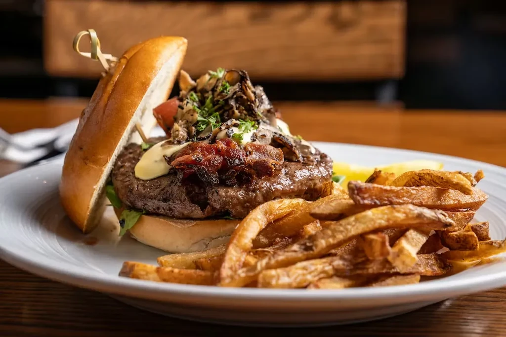 Gourmet burger with mushrooms, bacon, cheese, and rustic cut fries.