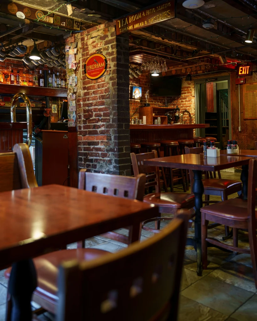Empty rustic pub interior with Fordham Brewing sign and well-stocked bar.