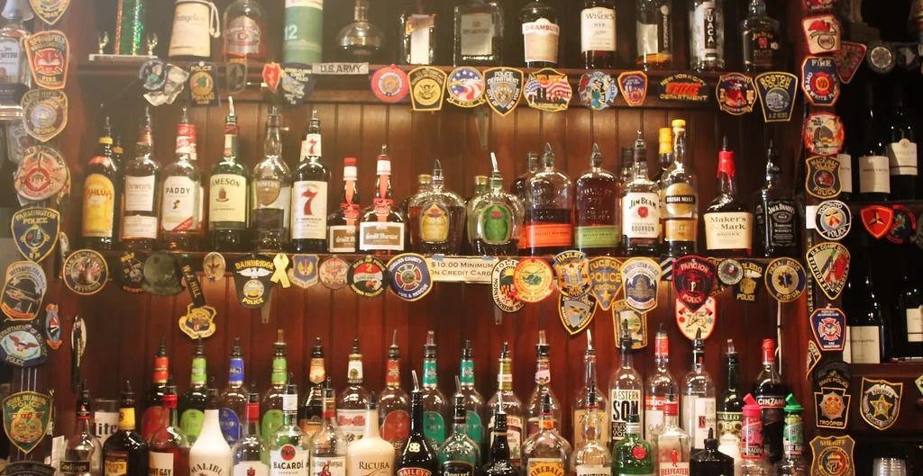 Bar shelves filled with liquor bottles and emergency service patches.