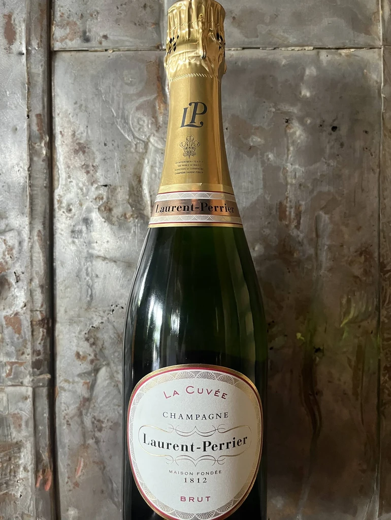 Laurent-Perrier 'La Cuvée' Brut Champagne bottle on distressed metallic background.
