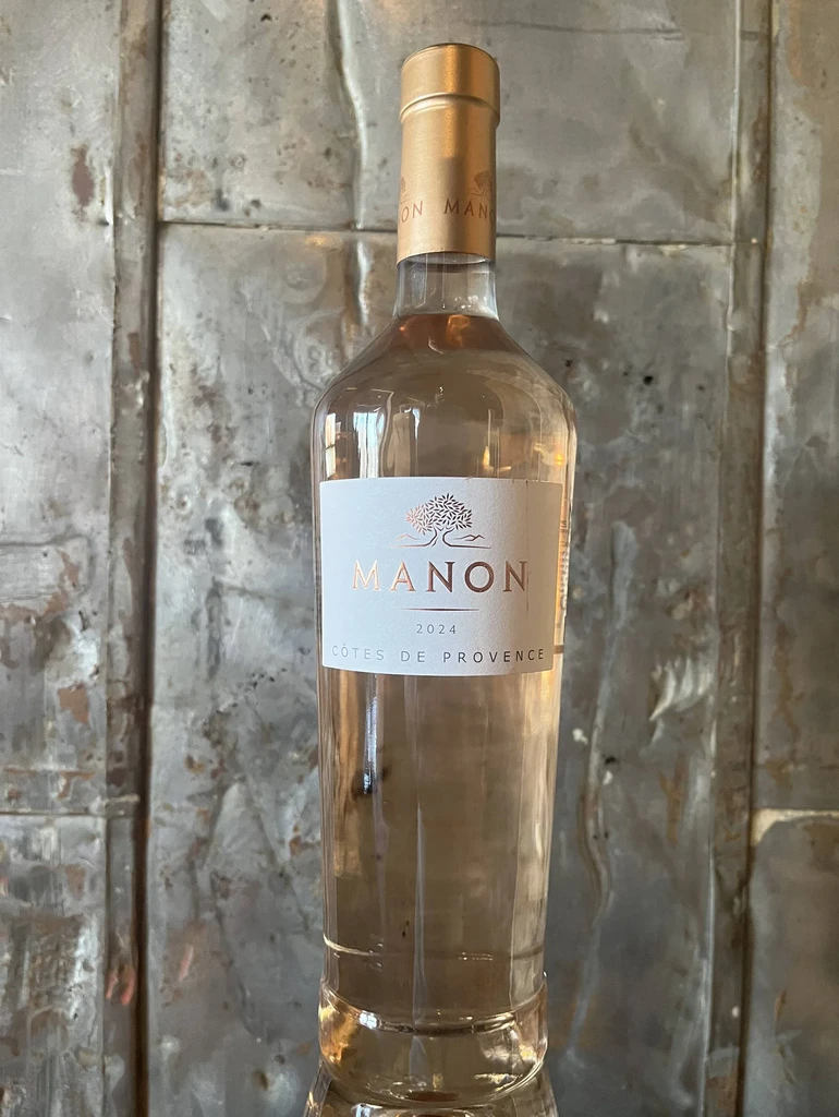 Manon 2024 rosé wine bottle on a textured metal wall.