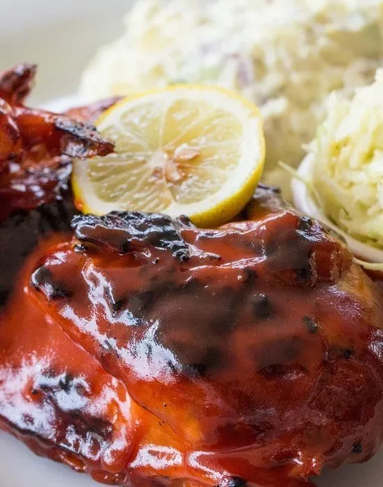 Dark glazed meat with lemon, creamy salad, and shredded cabbage.