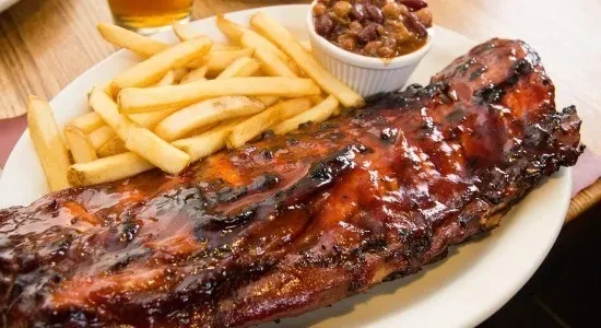 Full rack of barbecued ribs, french fries, and baked beans.