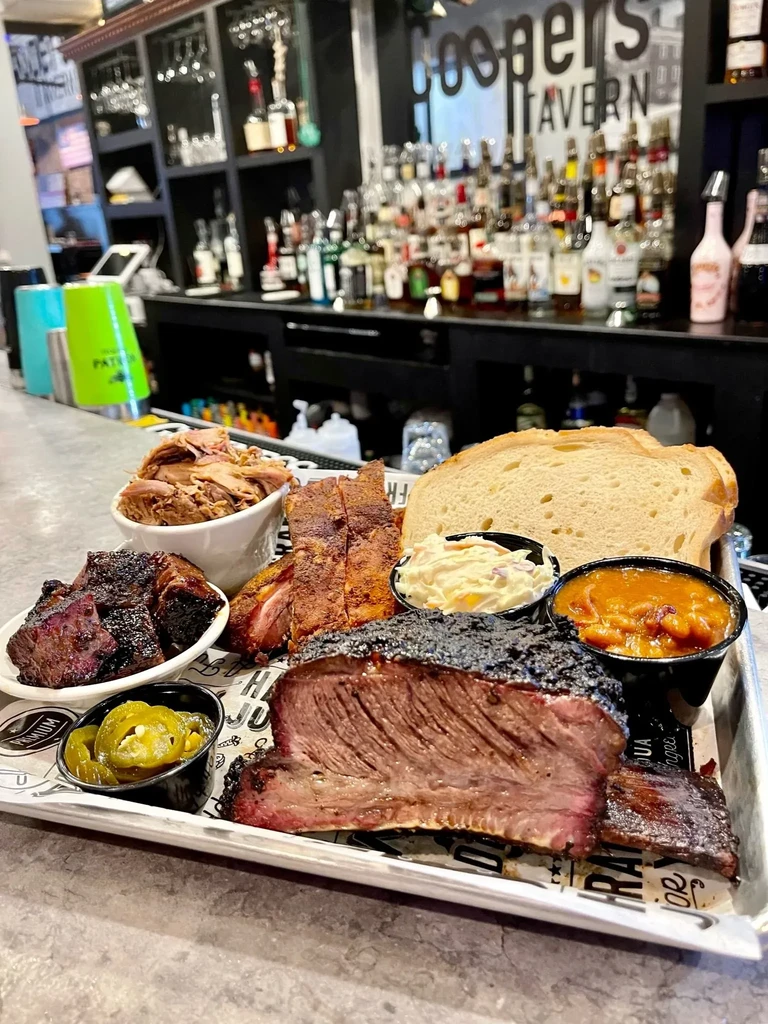 Barbecue platter with brisket, ribs, sides, and bread at Coopers TAVERN.