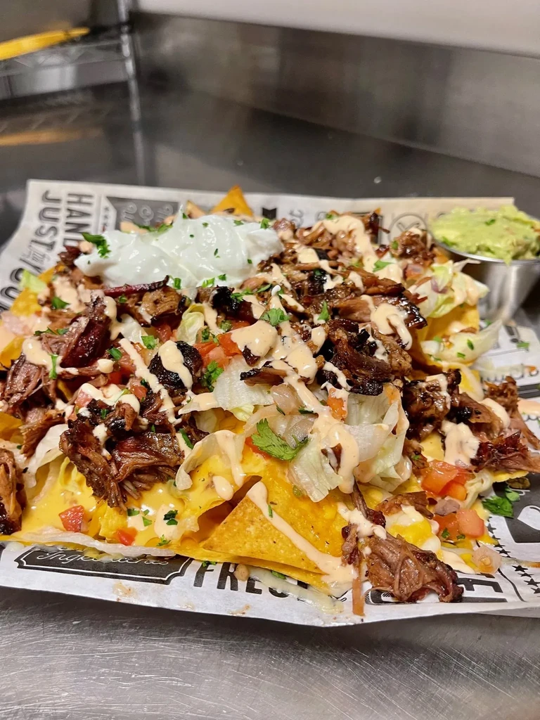 Overhead loaded nachos with meat, melted cheese, pico, sour cream, and guacamole.