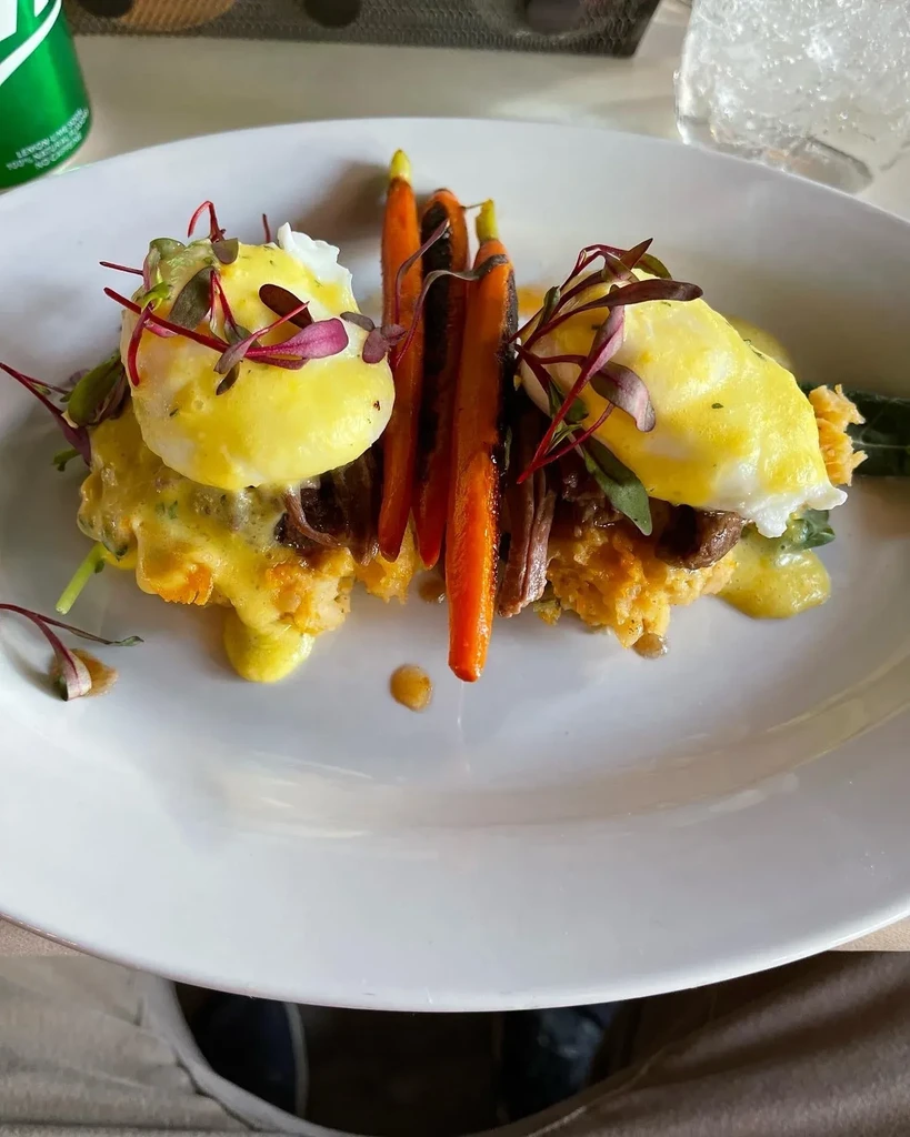 Artfully plated poached eggs, braised meat, hollandaise, and charred carrots.