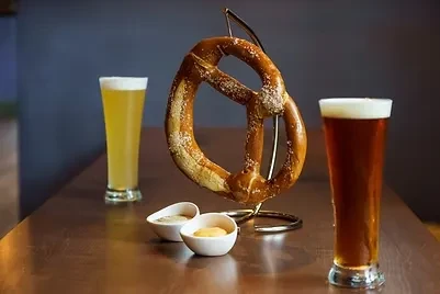 Large salted pretzel, two pilsner beers, and dipping sauces.