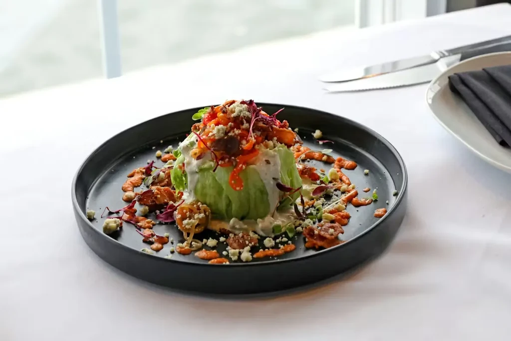 Wedge salad with blue cheese, red peppers, crispy bits, and microgreens.