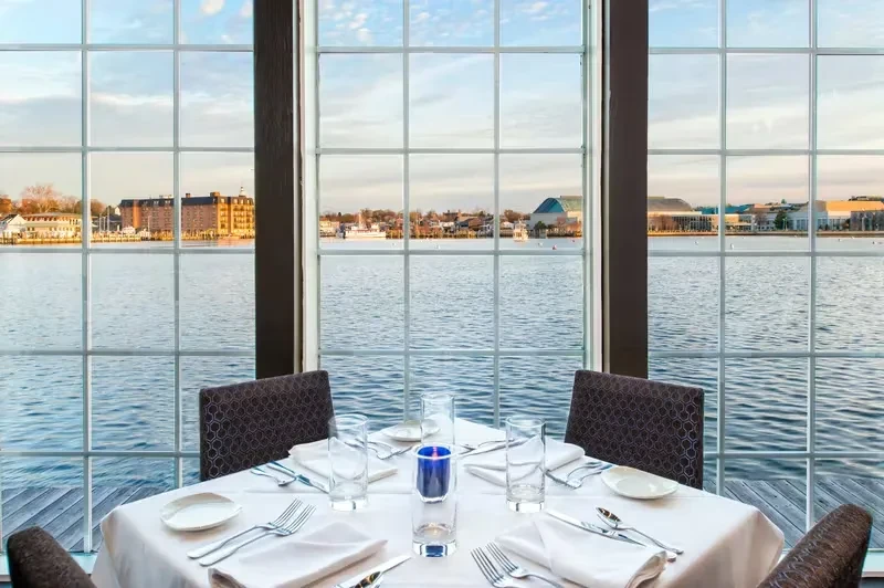 Elegant table set for four overlooking a panoramic waterfront city view.