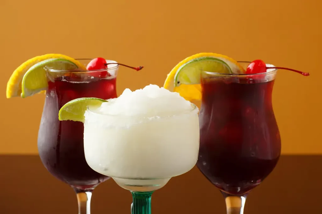 Three garnished cocktails: two red and one white frozen.
