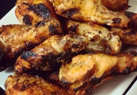 Seasoned, charred golden-brown chicken wings on a white plate.